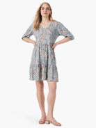 Beige tiered mini dress with teal leaf pattern, elbow-length sleeves, and V-neck.