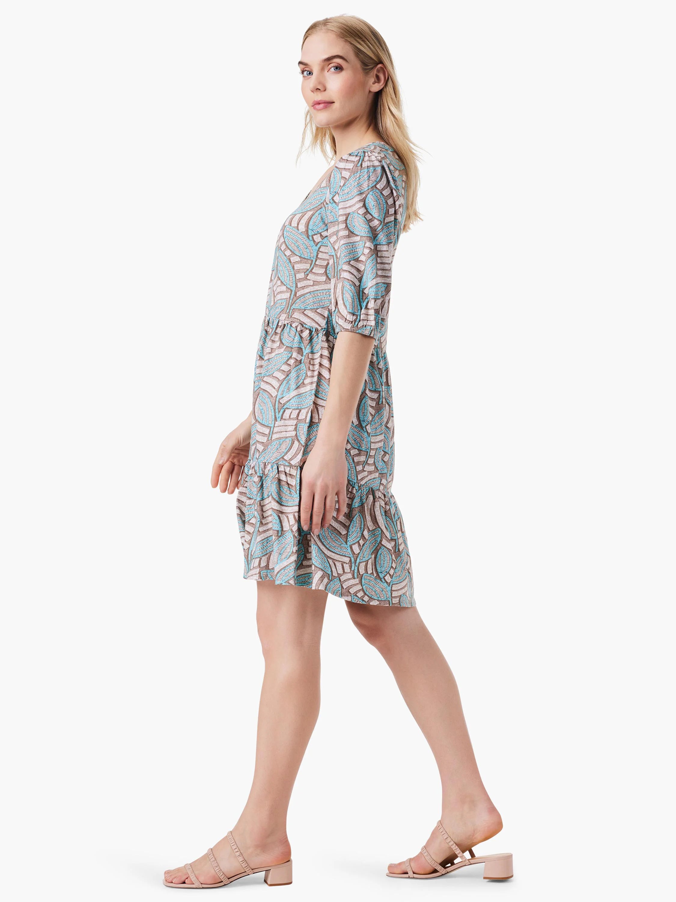 Beige mini dress with teal leaf pattern, elbow-length sleeves, and tiered skirt. V-neck.