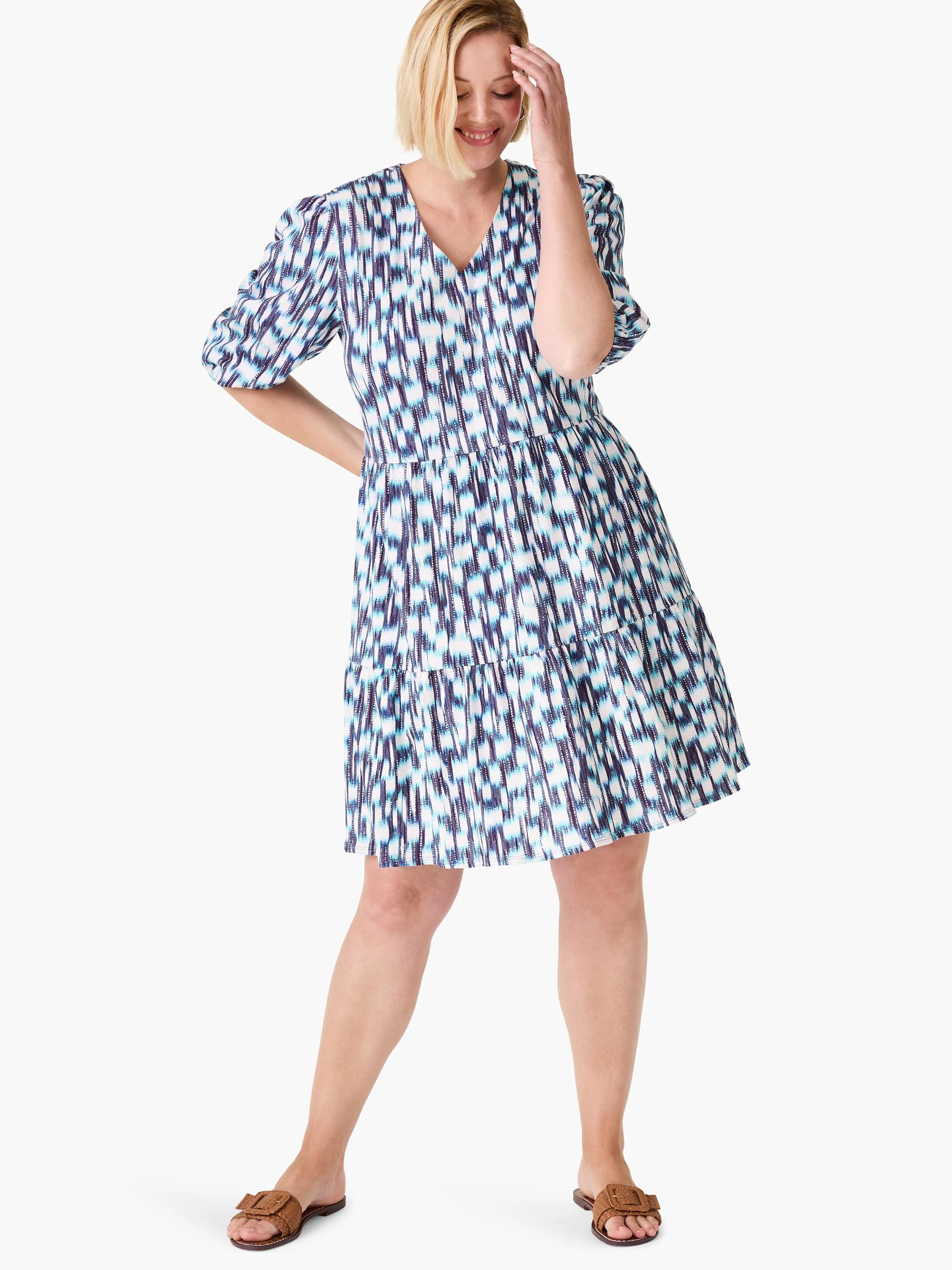 White tiered mini dress with blue and purple abstract print. Elbow-length sleeves, V-neck.