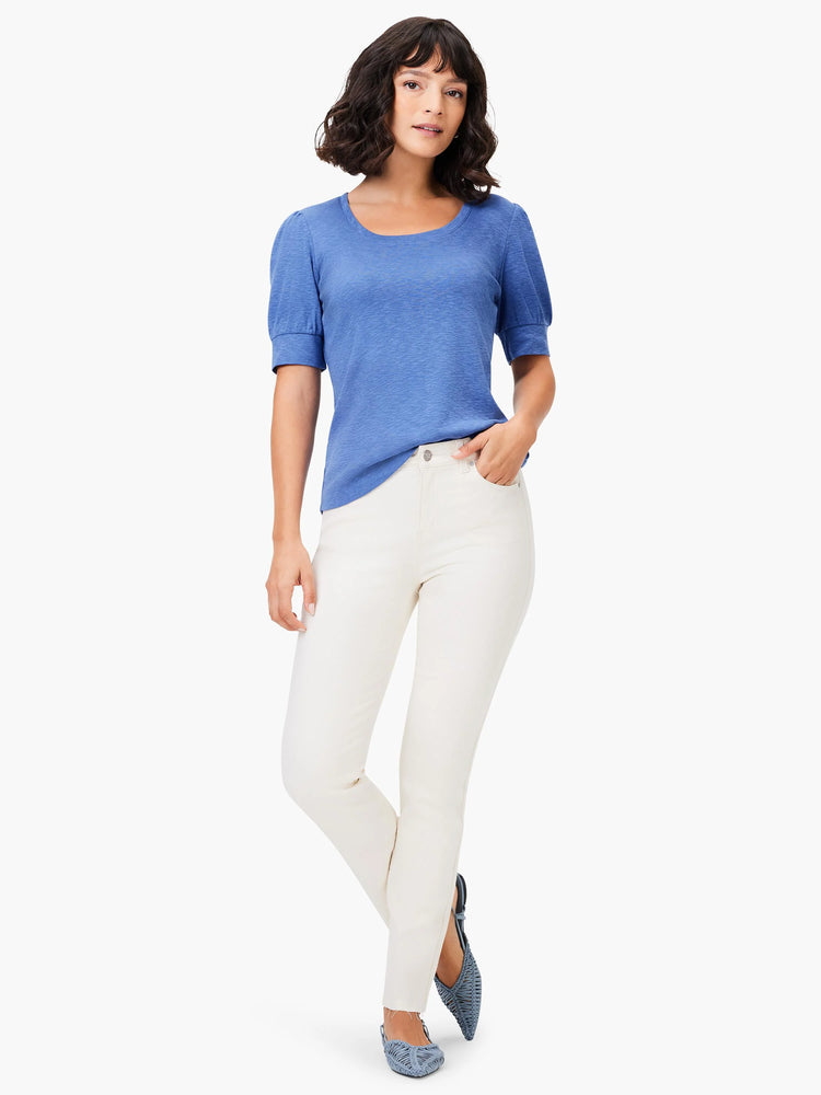 Blue scoop-neck tee with short, puffed sleeves.  Model also wearing off-white pants and blue shoes.