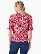 Pink, red, and purple abstract floral print top.  Ruched elbow-length sleeves. Split hem.  Back view.