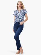 Short-sleeved split-neck top with blue, teal, and white abstract print.