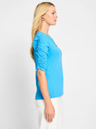 Bright blue, elbow-length sleeves with ruched detailing, split neckline.