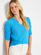 Bright blue, elbow-length sleeves with ruched detailing, split V-neck.