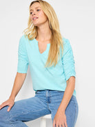 Light teal, short-sleeved t-shirt; ruched elbow sleeves; split neckline.