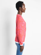 Pink long-sleeve top with darker pink leaf pattern. White underlayer visible at neckline and cuffs.