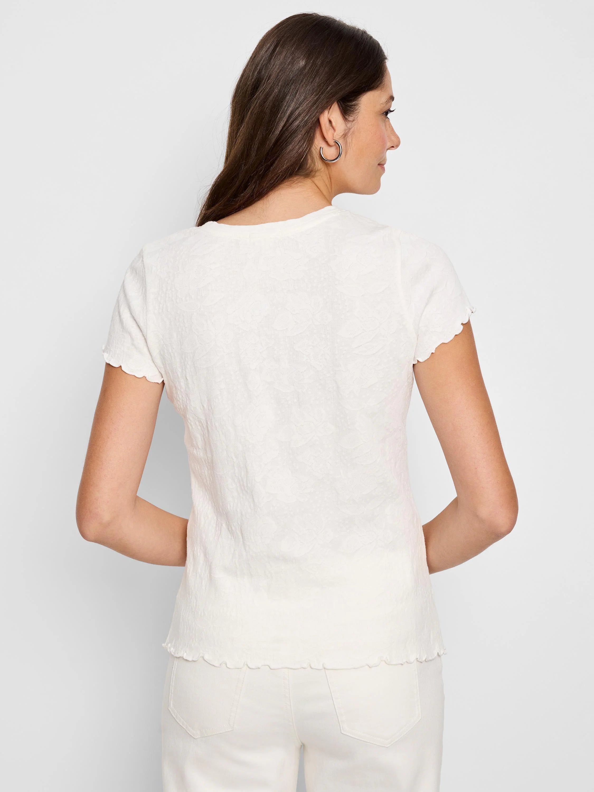 Off-white lace-knit t-shirt with short, scalloped sleeves and hem.  Back view.