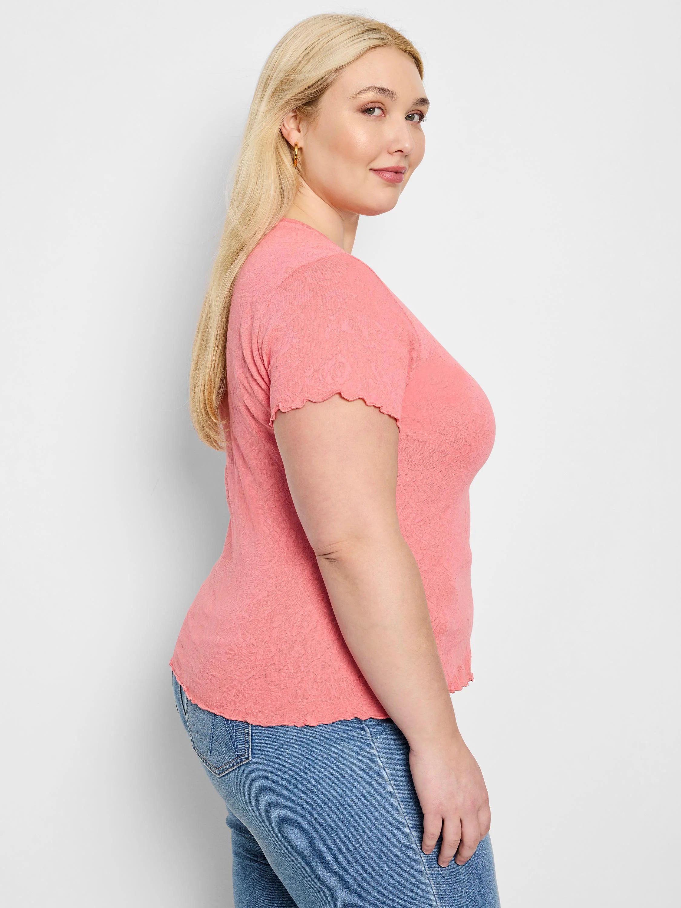 Pink textured knit t-shirt with scalloped edges on sleeves and hem.  Short sleeves.