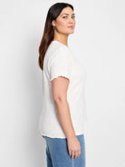 Off-white lace-knit t-shirt with short, ruffled sleeves.  Hem is also ruffled.