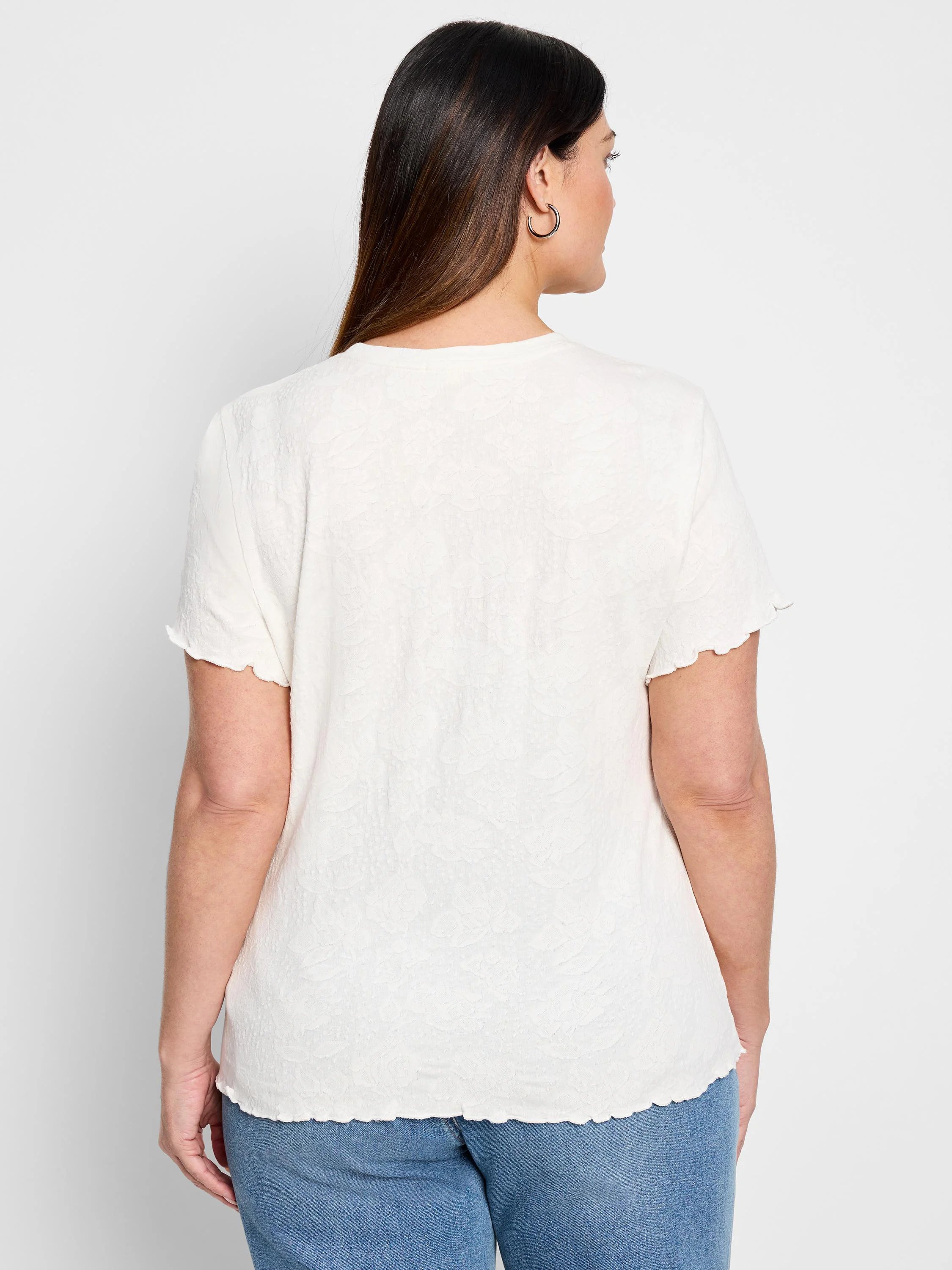 Off-white lace-knit t-shirt with short, scalloped sleeves.  Back view.