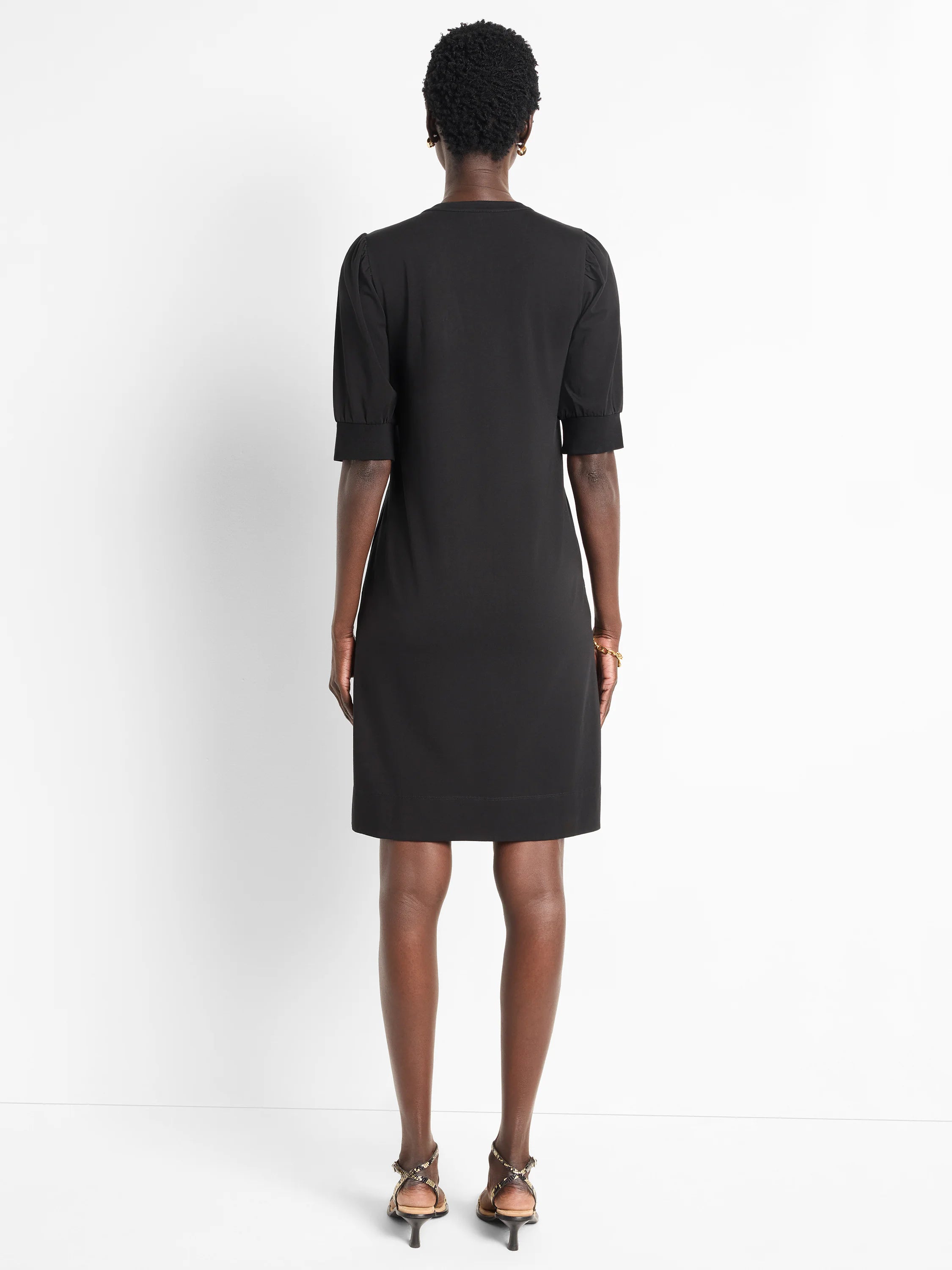 Black short-sleeved Henley dress, puff sleeves, straight hemline.  Rear view.