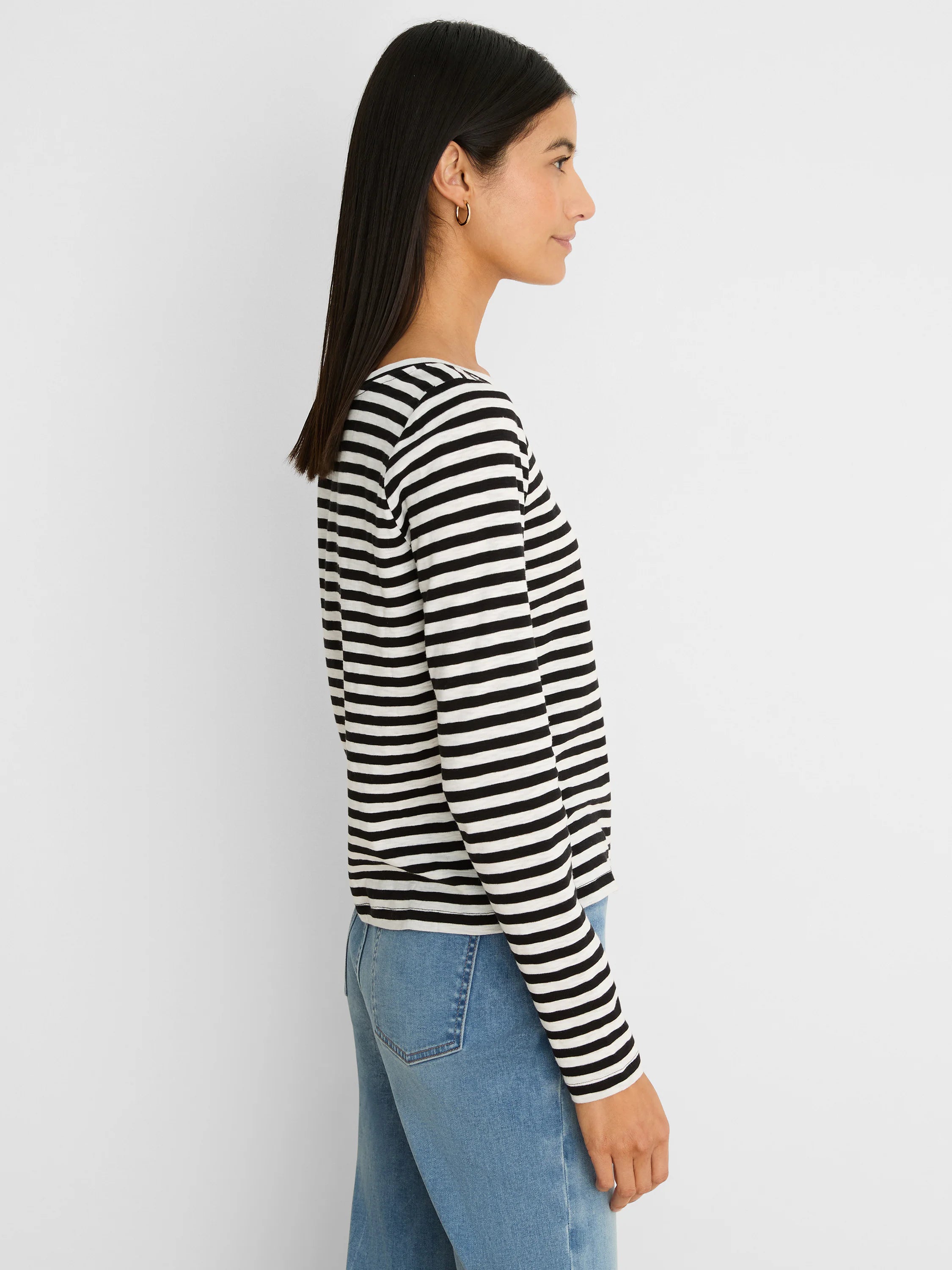 Woman wears a black and white striped long-sleeve tee. Features a boat neck and ribbed fabric.