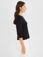 The model wears a black knit top with a wide neck and three-quarter sleeves in a standard fit.