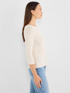 This relaxed fit cream heathered knit top features a boat neckline and three-quarter sleeves.