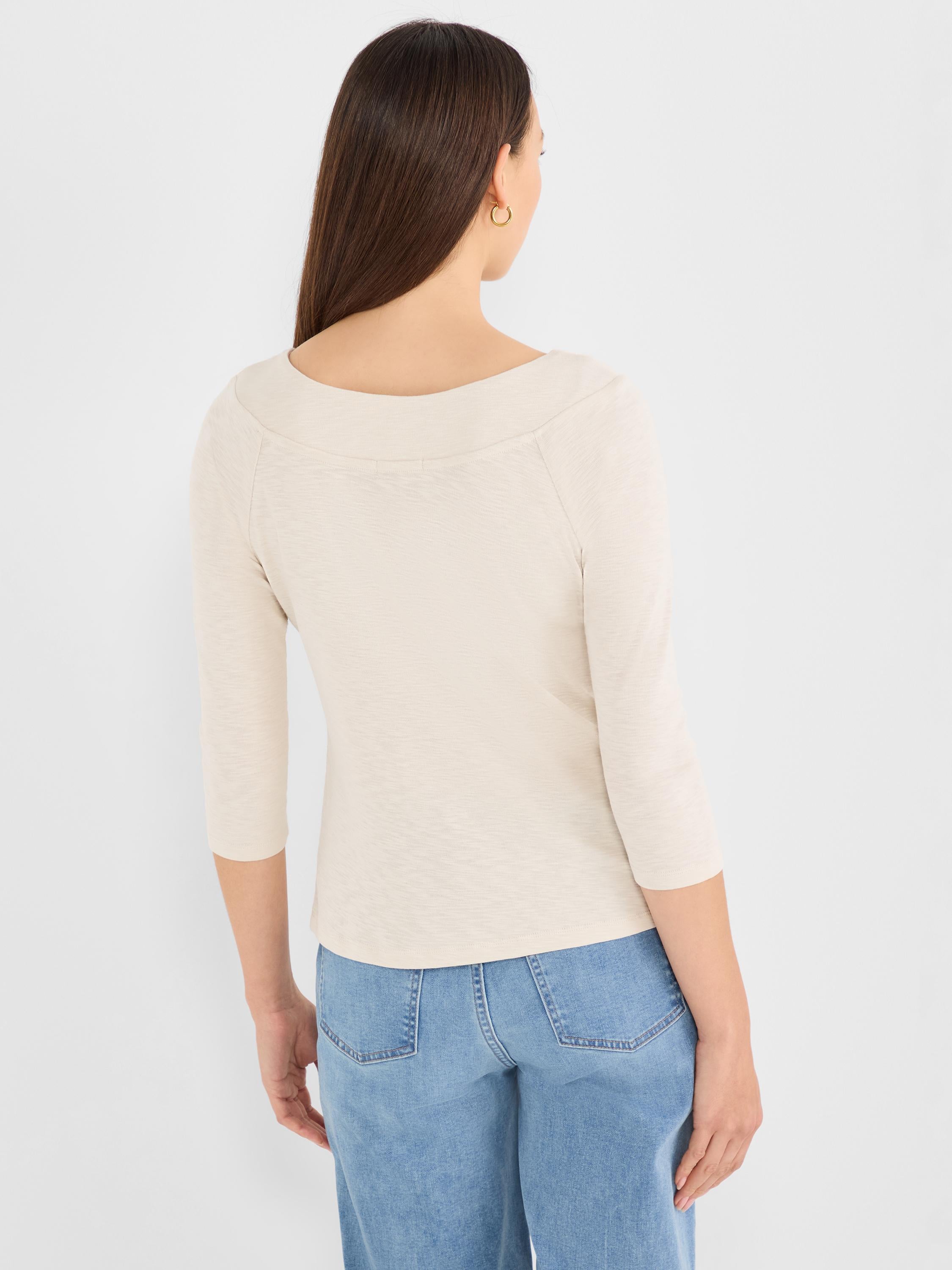 A fitted beige top with subtle texture features three-quarter sleeves and a wide, structured boat neckline.