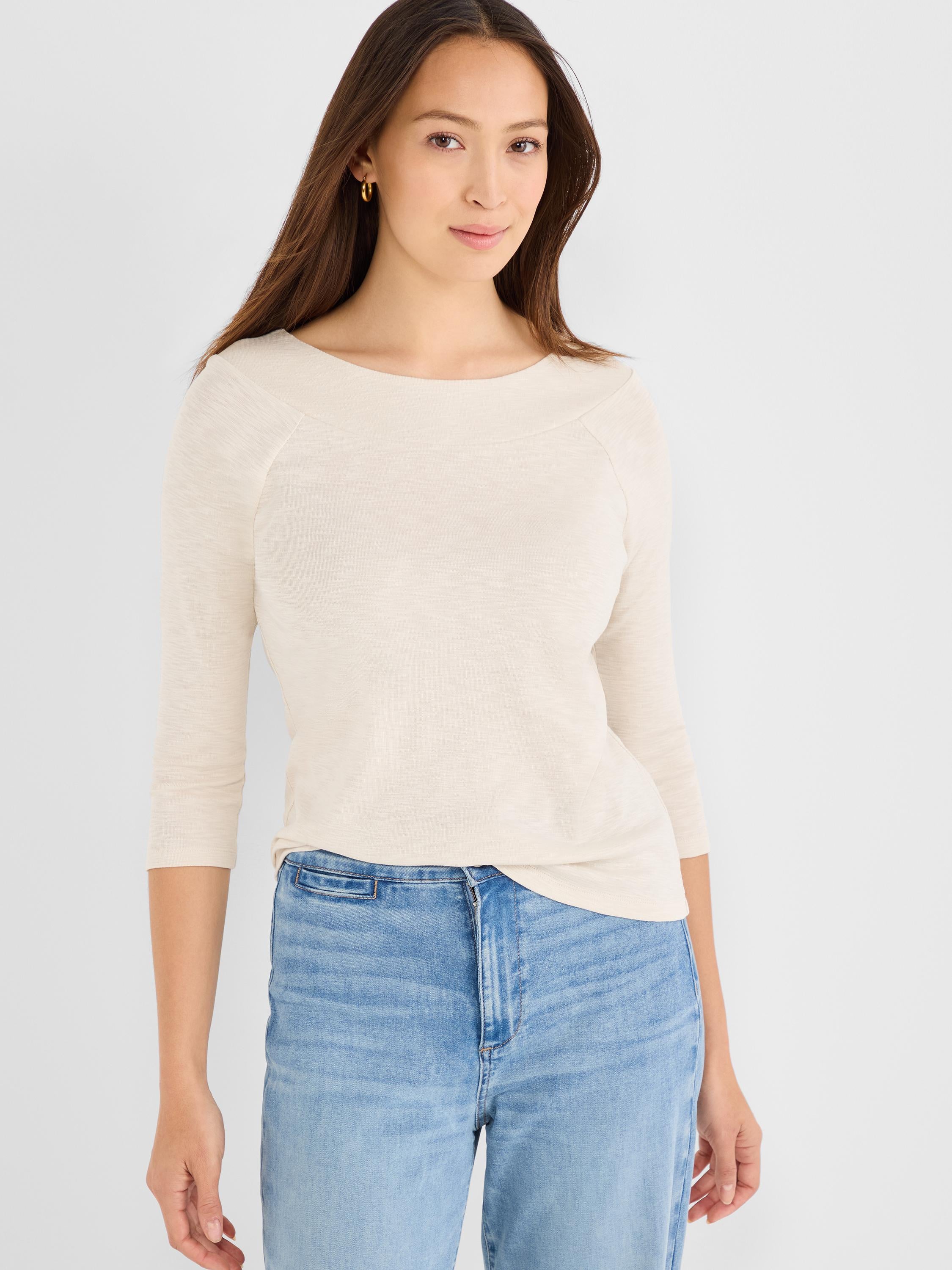 Model wears a fitted cream heathered knit top featuring three-quarter raglan sleeves and a wide boat neck.
