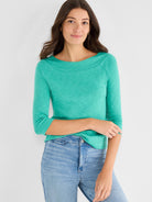 Fitted heathered teal knit top with raglan three-quarter sleeves and a wide boat neckline.