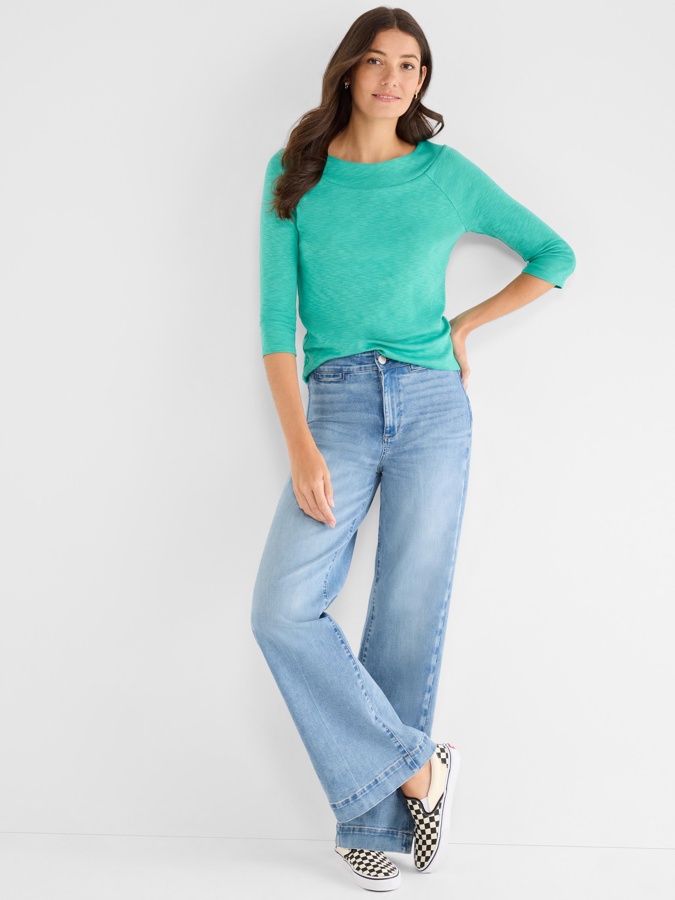 Model wears a fitted aqua three-quarter sleeve boatneck top with high-rise light wash wide-leg denim jeans.