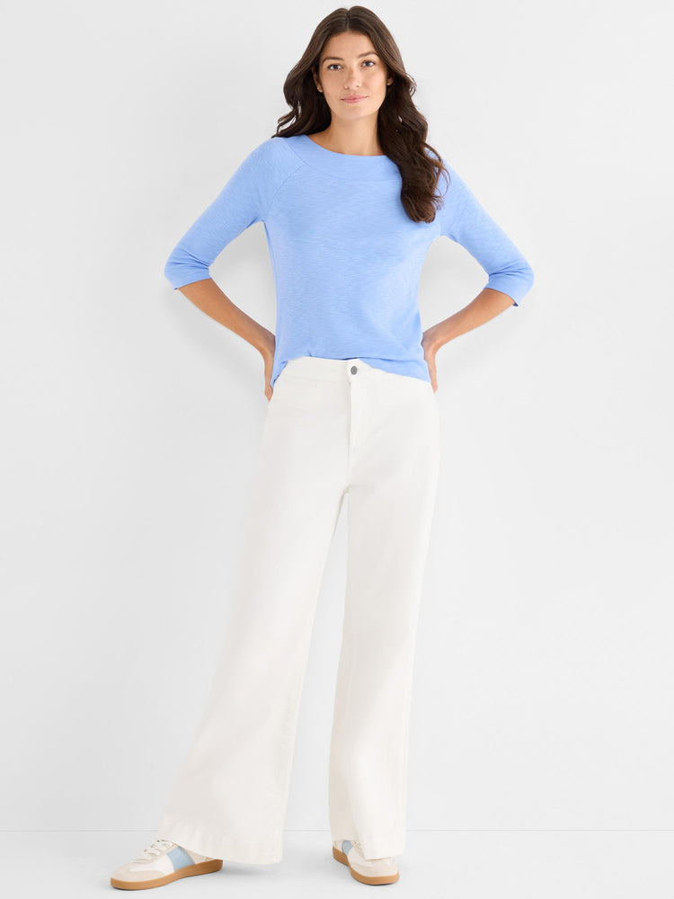 The model wears a fitted periwinkle knit top with three-quarter sleeves and white wide-leg high-rise trousers.
