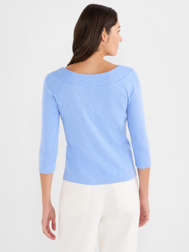 Slim-fit light blue slub knit top with three-quarter sleeves and a wide bateau neckline on the model.
