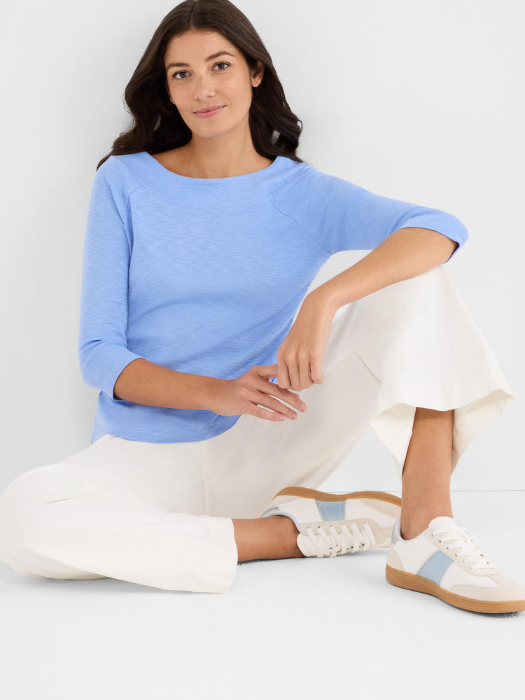 Slim-fit light blue slub knit top featuring a boat neckline and comfortable three-quarter raglan sleeves.