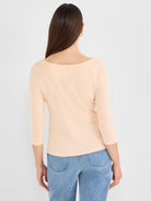 A slim-fit light peach slub knit top featuring 3/4 sleeves and a wide boat neck.