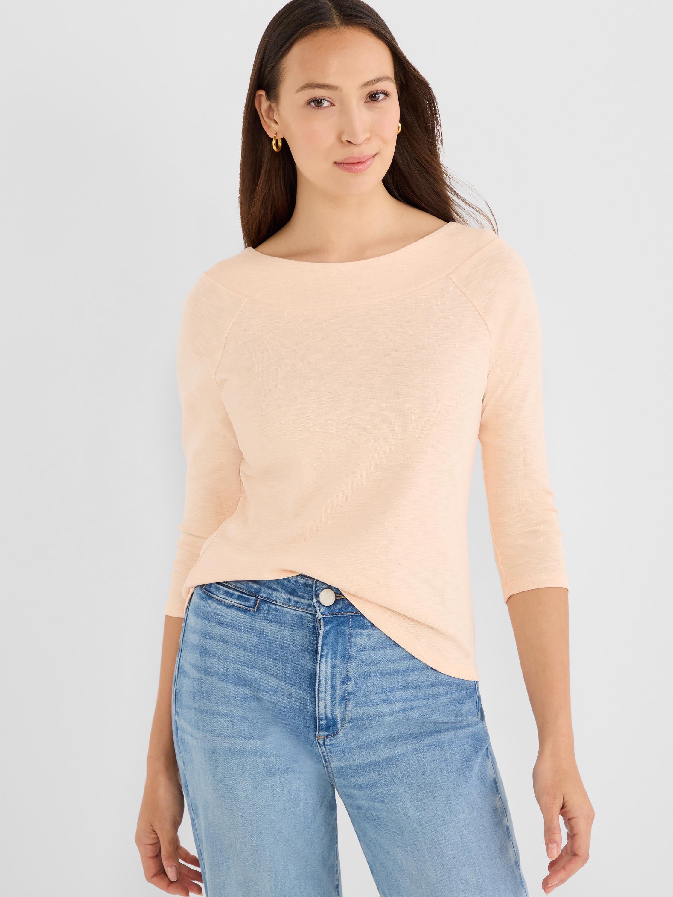 This pale peach top features a boat neck, raglan sleeves, and a three-quarter sleeve length.