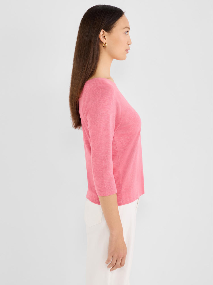 A model wears a fitted, heathered pink top featuring a boat neckline and three-quarter sleeves.