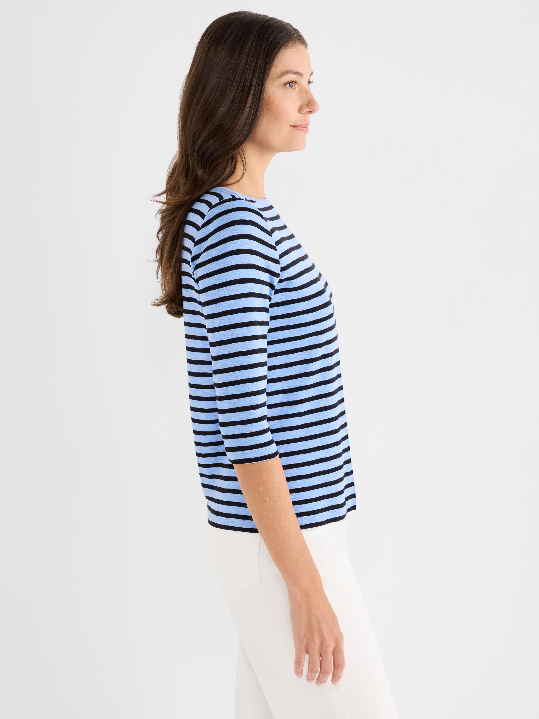 A model wears a relaxed fit light blue and black striped tee with a wide crew neck and three-quarter sleeves.