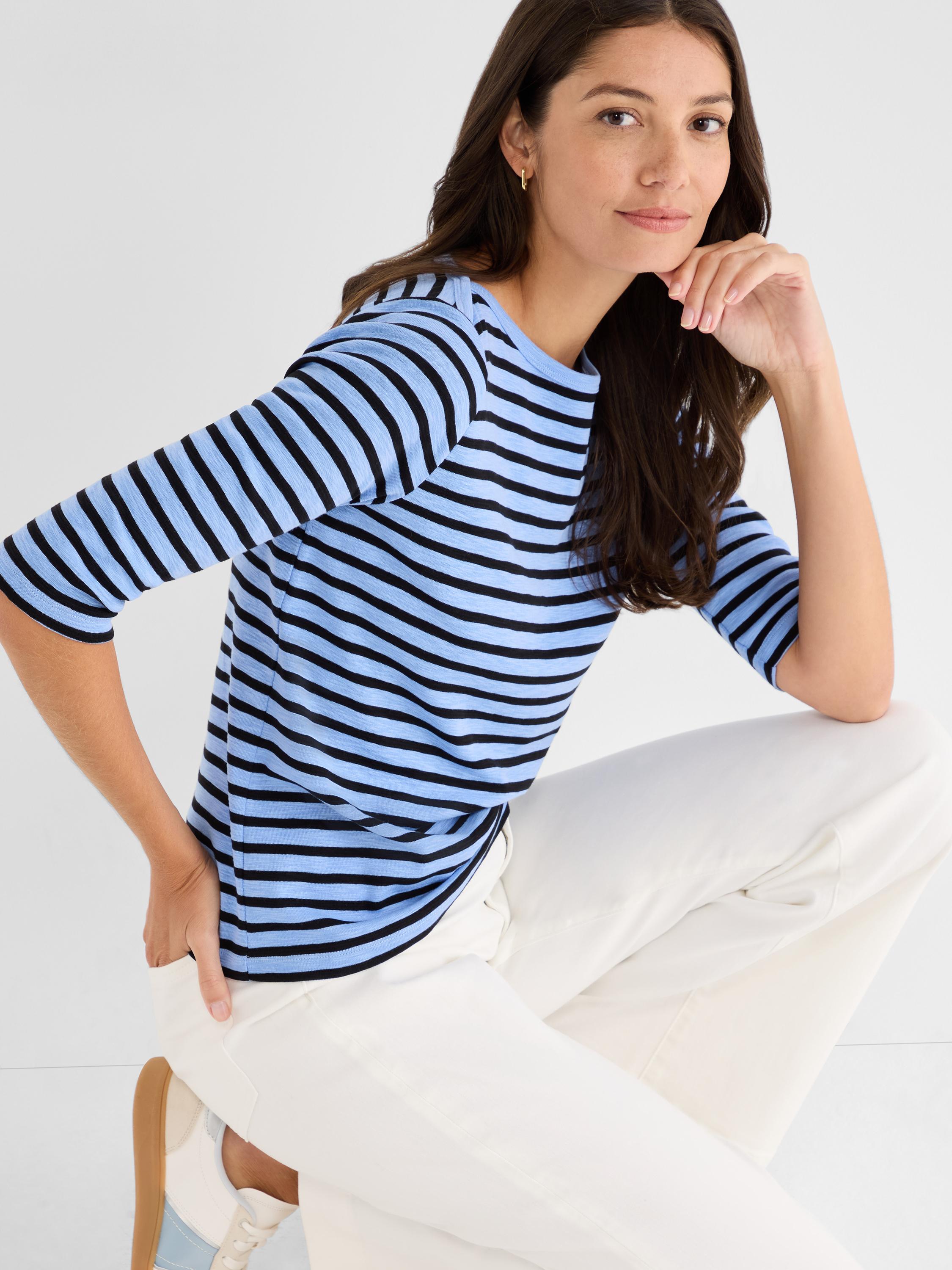 Relaxed fit blue and black Breton stripe knit top with three-quarter sleeves and a crew neck, styled with white pants.