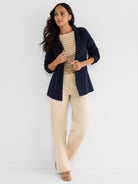 Dark blue knit cardigan blazer with a notched lapel and patch pockets, worn open and hip-length.