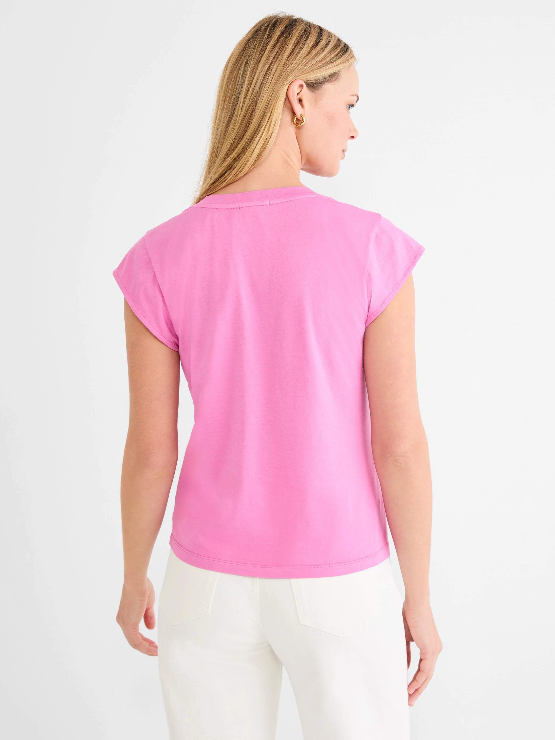 Pink cap sleeve tee, back view, worn by a model in white pants.
