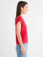 Red cap sleeve V-neck tee on a woman, shown in profile.