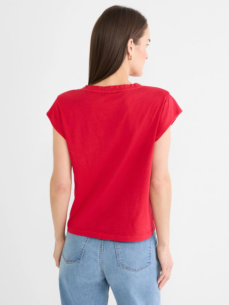 Back view of a model wearing a red cap sleeve tee with a relaxed fit and rounded back neck. Worn with light jeans.