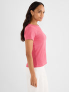 The model wears a fitted pink heathered ribbed knit tee shirt with short sleeves and a crew neck.
