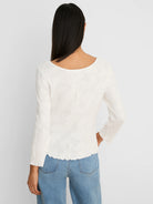 Off-white 3/4 sleeve top with floral lace knit texture, scoop back, and scalloped edges.