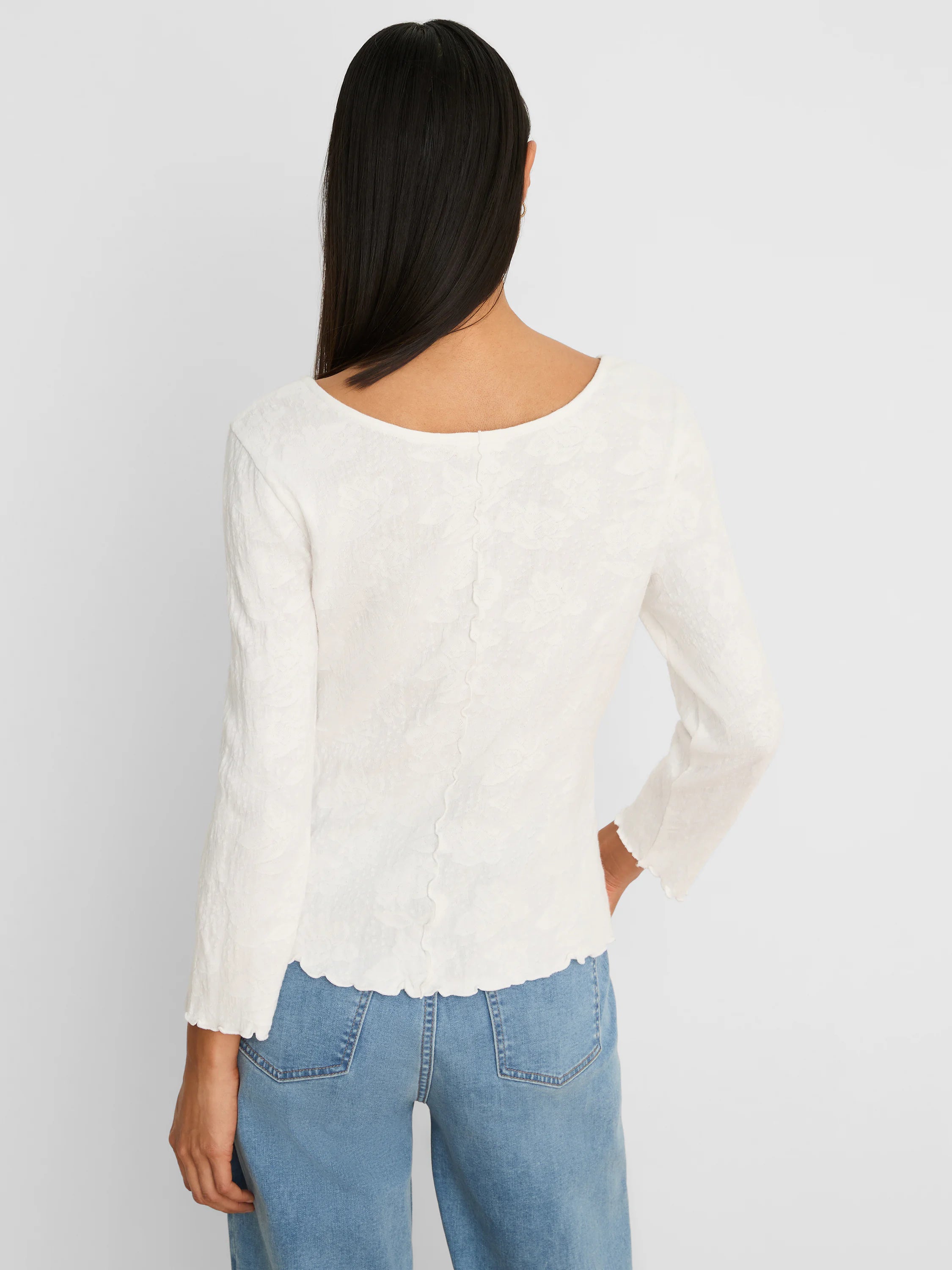 Off-white 3/4 sleeve top with floral lace knit texture, scoop back, and scalloped edges.