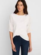 Off-white cotton tee with sheer 3/4 linen sleeves, visible blue stitching, and a boat neck.