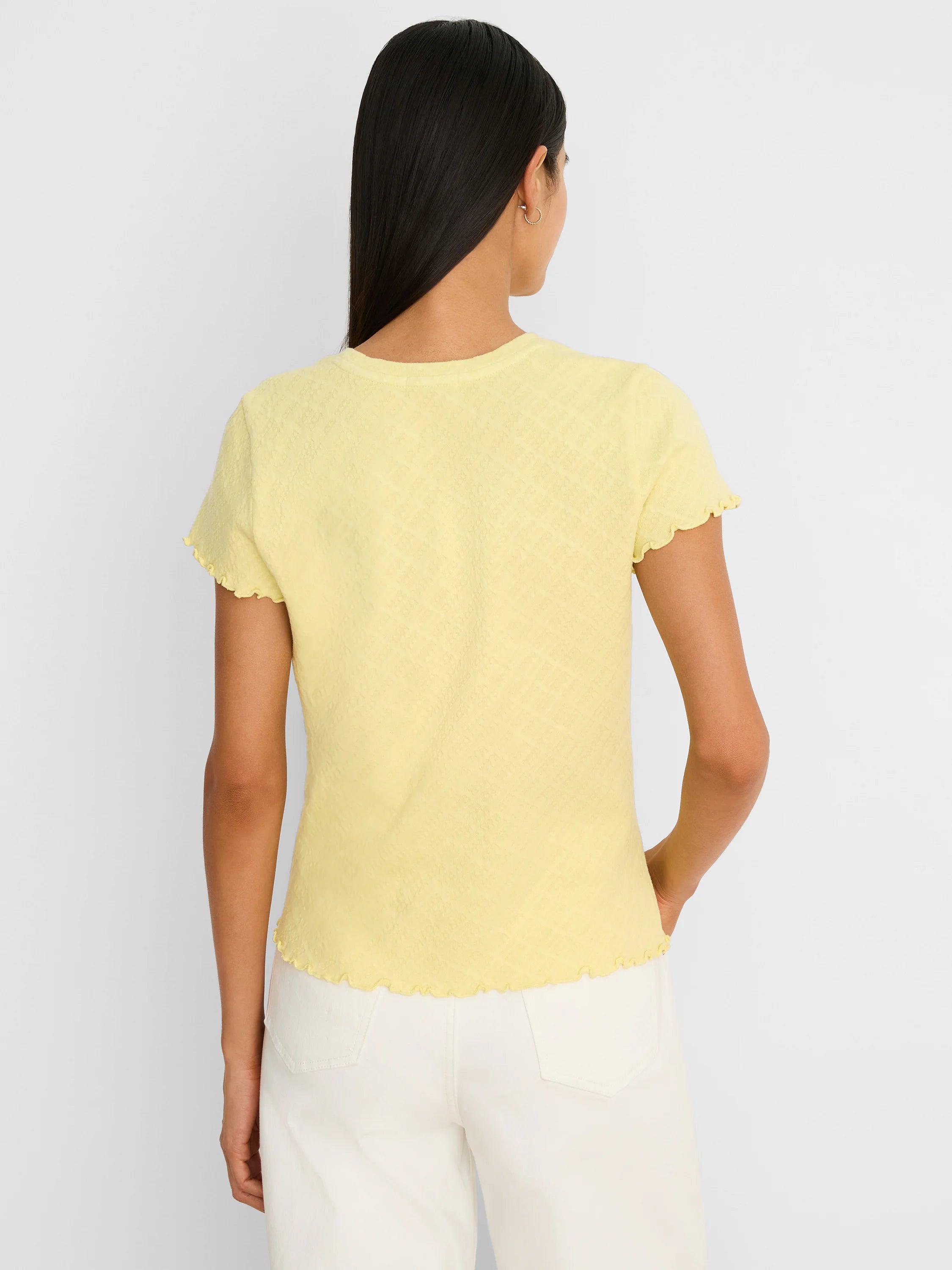 Light yellow lace-knit t-shirt with subtle textured pattern, short ruffled sleeves, and ruffled hem. Back view.