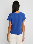 Blue T-shirt with a lace knit diamond pattern, short sleeves, and ruffled trim on the neckline, sleeves, and hem.