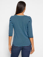 Back view of a woman in a 3/4 sleeve boat neck tee with alternating navy and light blue horizontal stripes.