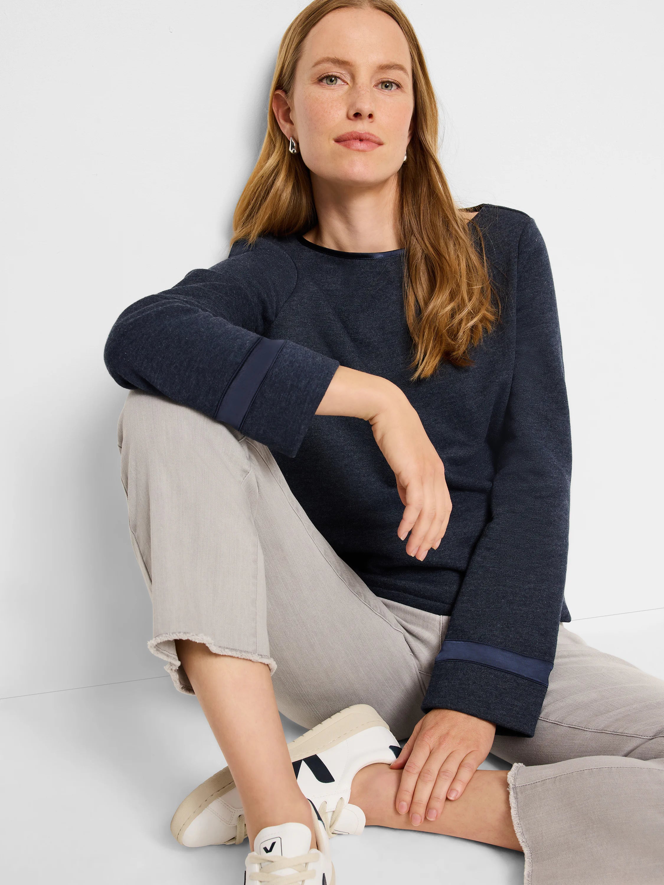 Dark-blue sweater with darker-blue ribbon trim at neckline and cuffs.  Model seated wearing light-grey pants.