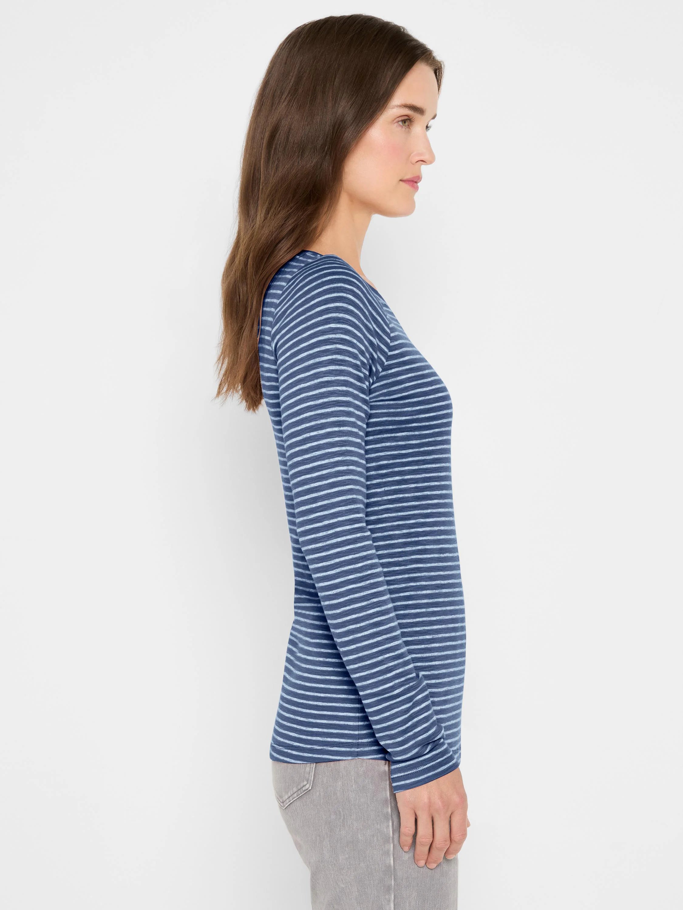 Blue long sleeve boat neck tee with horizontal light blue stripes, worn by a model in profile.
