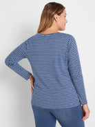 Model wears a long-sleeve boat neck tee with navy and light blue horizontal stripes. Back view.