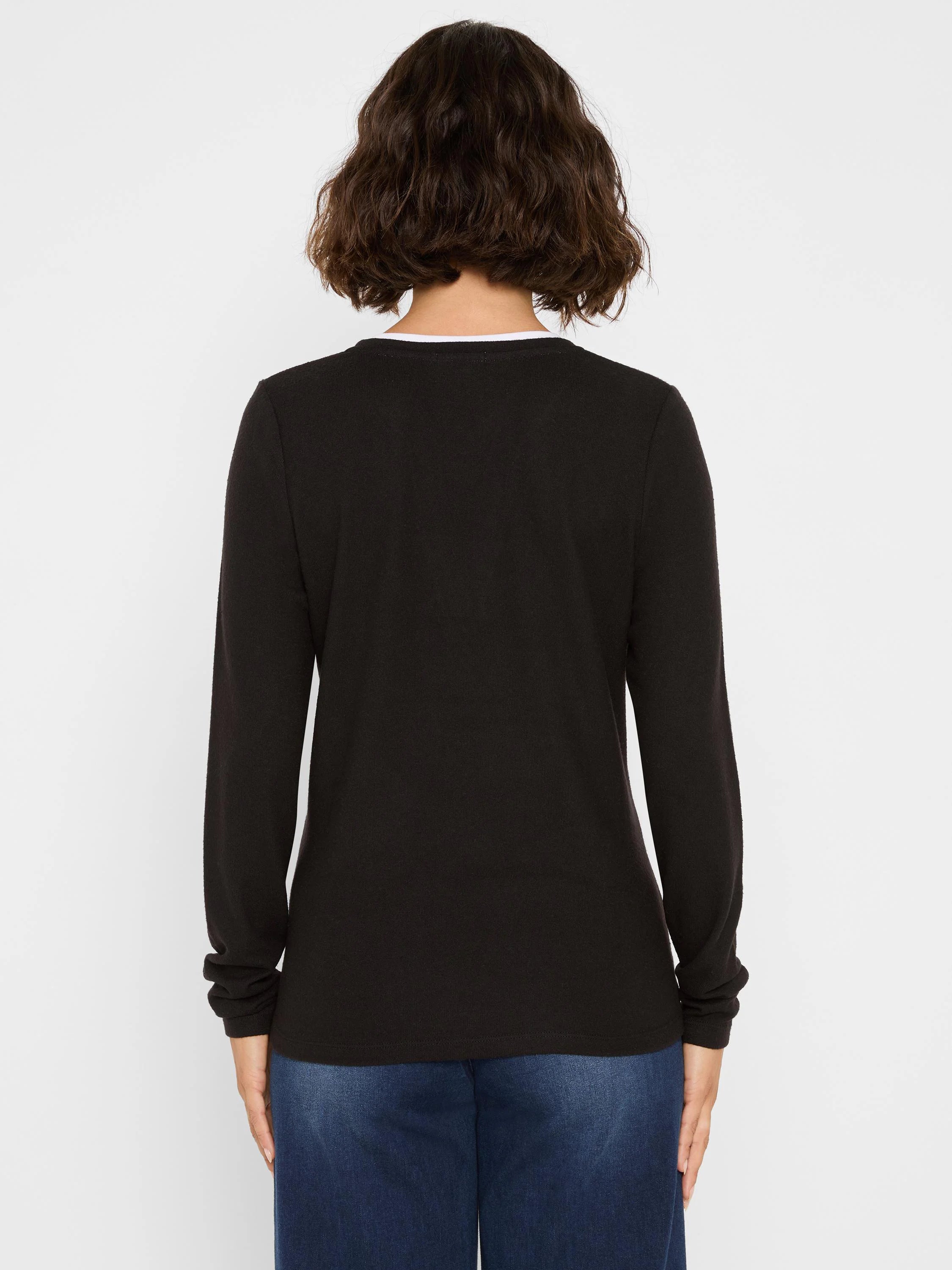 Black long-sleeve jersey tee with a visible white inner layer at the back neck. Person shown from behind.