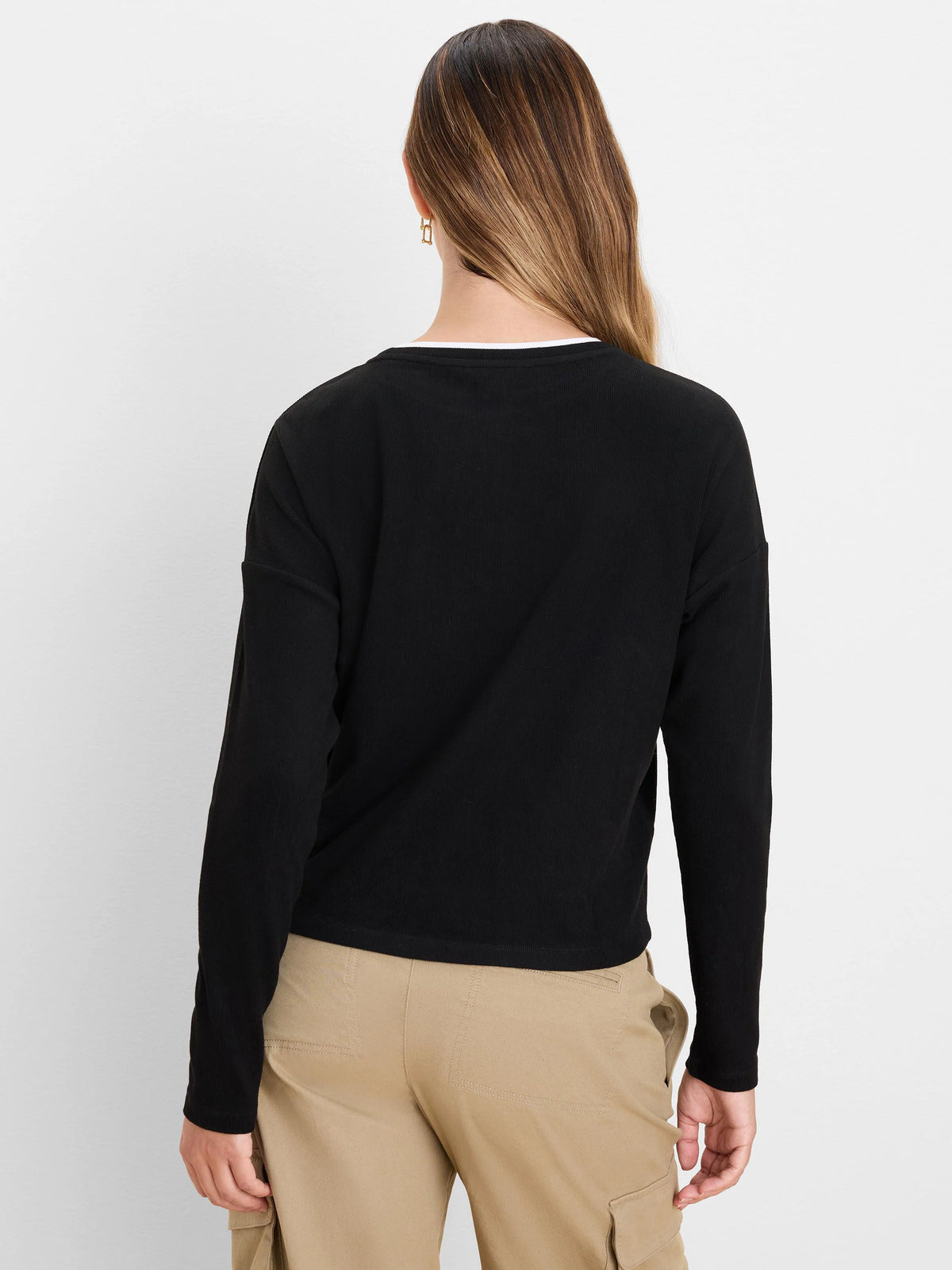 Black long-sleeve ribbed top, white second layer visible at the round neck. Back view of top.
