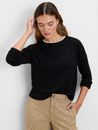 Black ribbed long-sleeve top with a white layer visible at the neckline.