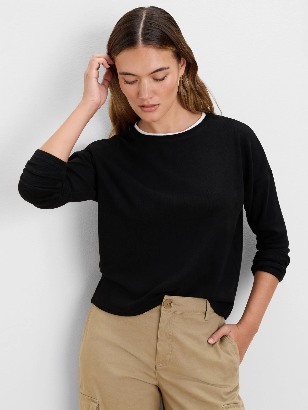 Black ribbed long-sleeve top with a white layer visible at the neckline.