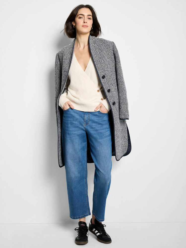 Black & white herringbone pattern top coat, dark navy trim.  Model wears it over a cream sweater and blue jeans.