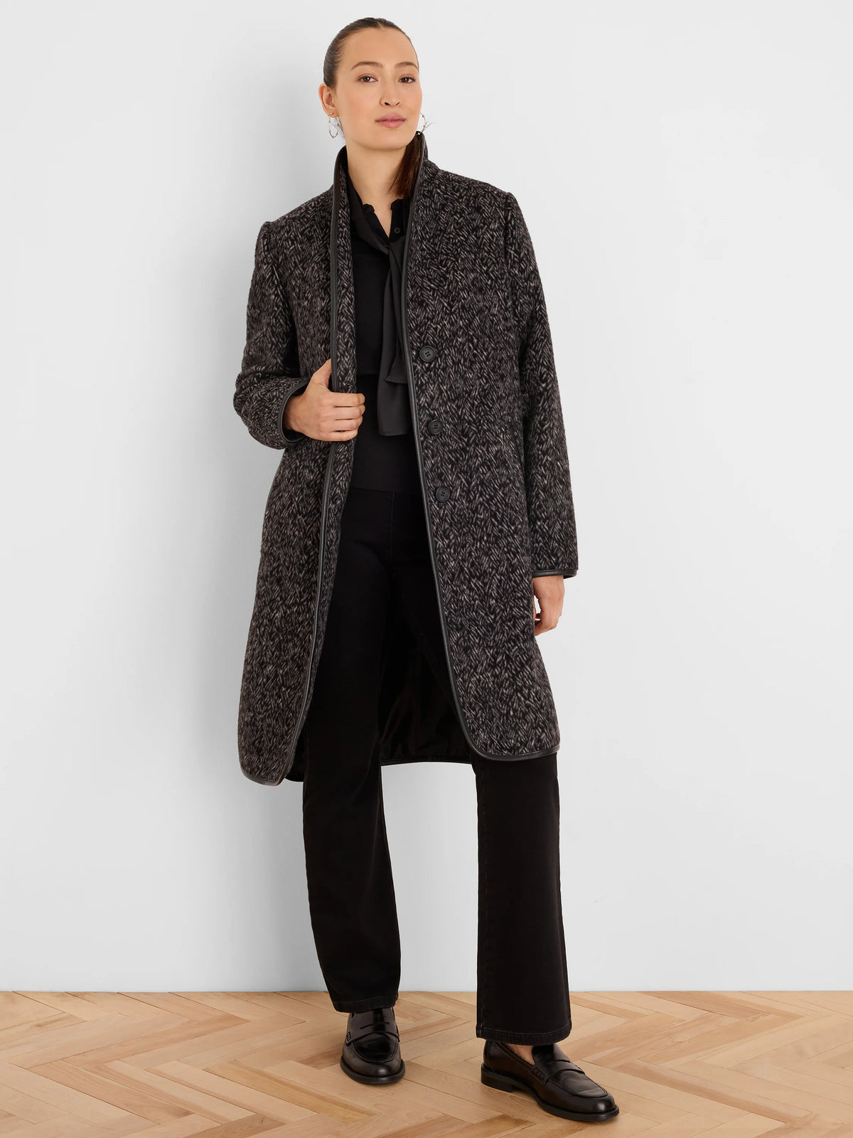 Mid-length dark gray jacquard coat with light flecks, subtle herringbone pattern, black trim on edges, and front buttons.